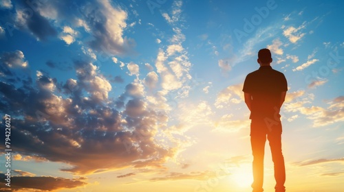 Silhouetted man standing under majestic sunset sky full of clouds