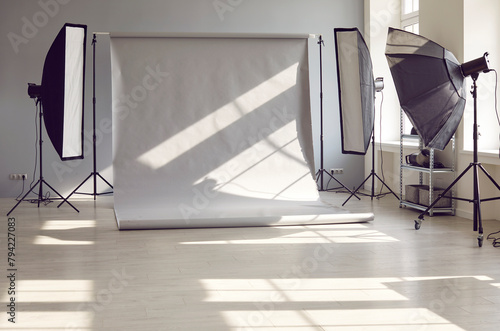 Interior of an empty modern photo studio with professional lighting equipment of rectangular softbox and octabox against gray background prepared for photography work photo session. photo