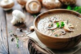 A bowl of mushroom soup on a rustic wooden table. Perfect for food blogs and recipe websites