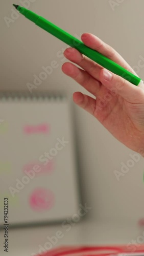 Girl removes cap from green felt-tip pen drawing picture photo