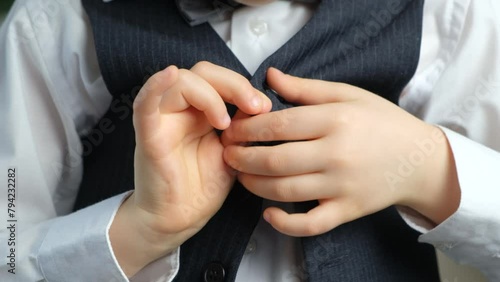 Little child learning to fasten and unbutton clothes, hands close-up photo