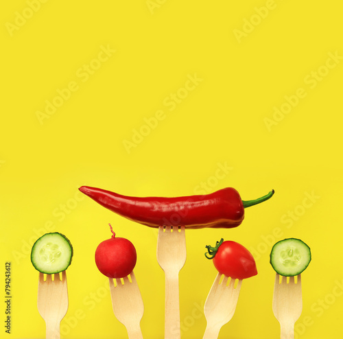 Pepper  tomato  cucumber and radish on wooden disposable forks  close-up  yellow background. Healthy eating concept. Fresh vegetables in the diet. Vegetables on a black background. Space for text