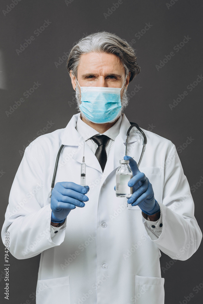 A senior doctor in a protective mask and gloves is preparing for an injection, holding a vaccine and a syringe. A senior doctor in a protective mask and gloves is preparing for an injection, holding a vaccine and a syringe.