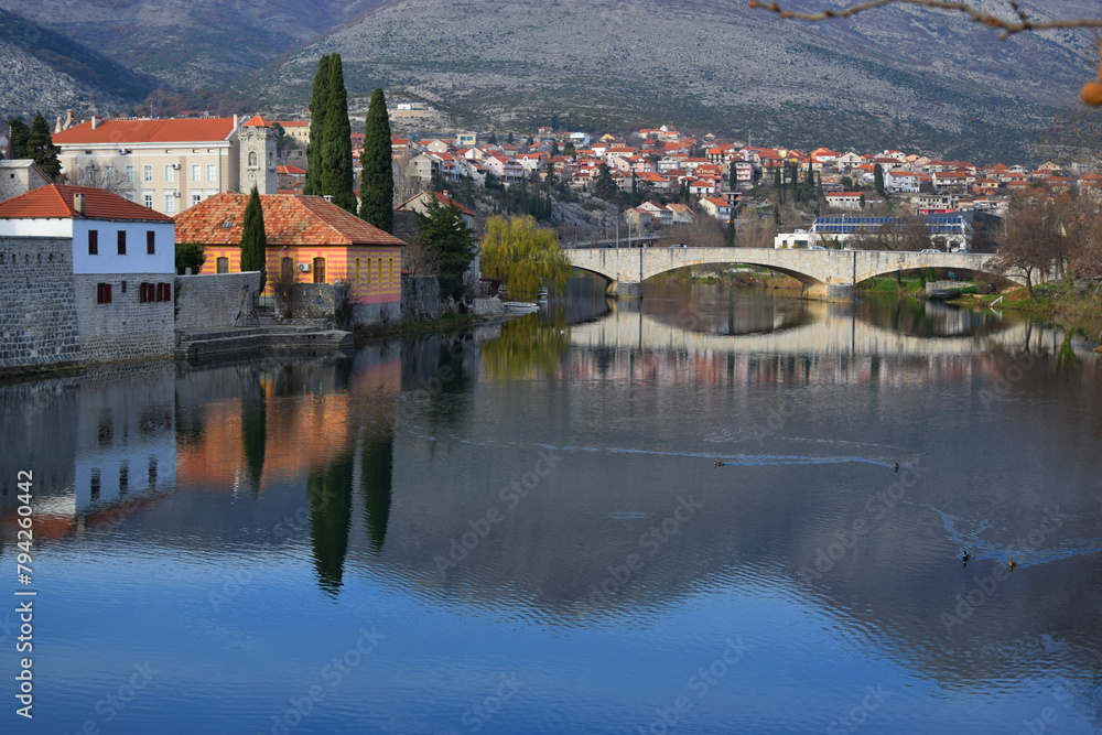 Obraz premium Bosnia and Herzegovina, Trebinje city, old town stone bridge and river on a sunny autumn day with clear blue sky. Mountains in the background.