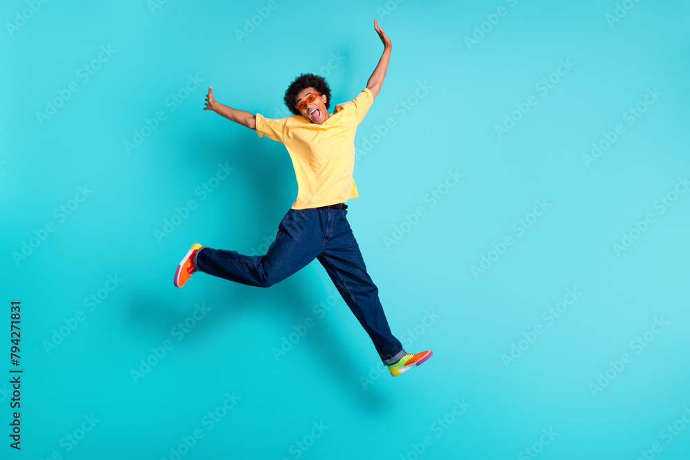 Full size photo of carefree man wear oversize t-shirt denim pants in glasses flying hands like wings isolated on teal color background