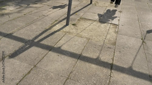On the ground are the shadows of children swinging on a swing on a playground in a city park on a hot sunny day. photo