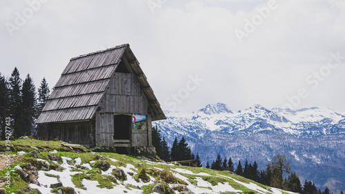 Mountain hut of in Planina Zajamniki on a cloudy day with the snowy mountain at he background photo