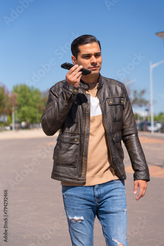 Handsome man listening to audio on mobile phone while walking down the street