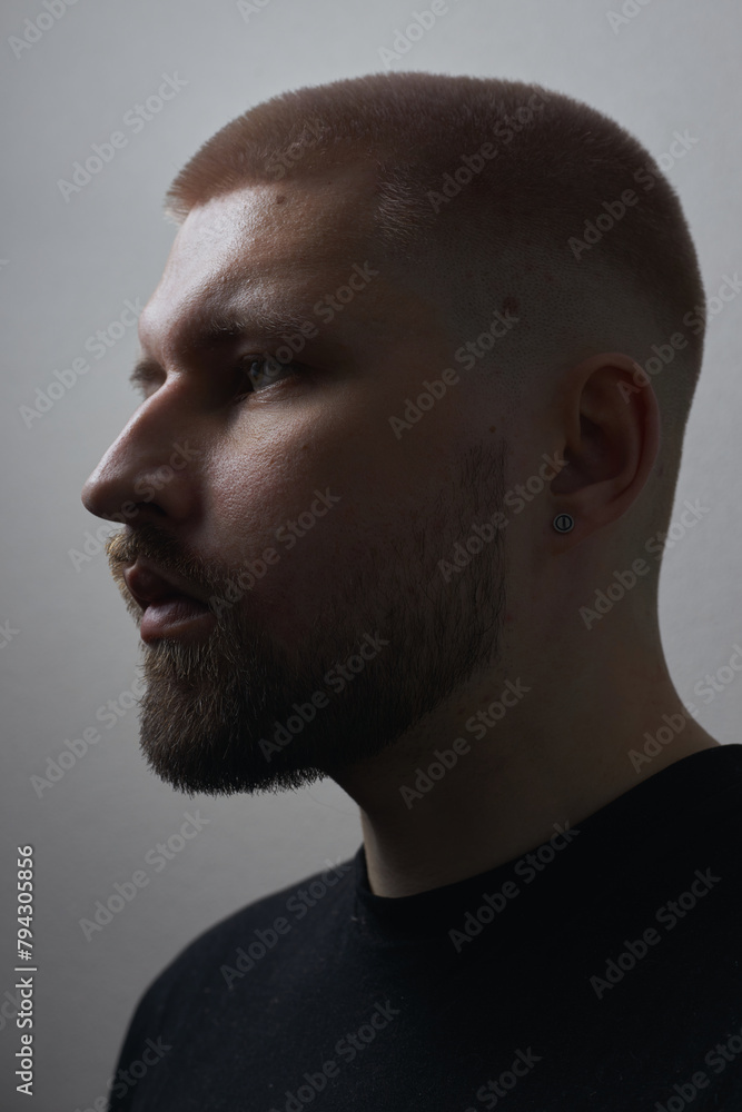 Obraz premium Portraits of a Millennial guy with a short haircut and beard, earrings in his ears