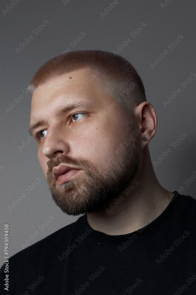 Portraits of a Millennial guy with a short haircut and beard, earrings in his ears Portraits of a Millennial guy with a short haircut and beard, earrings in his ears
