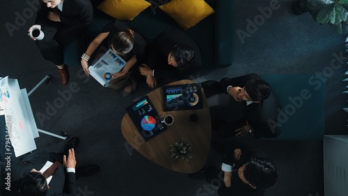 Top down view of business people listen businessman present idea while making decision. Group of diverse team making a decision to invest start up project while hold tablet display graph. Directorate.