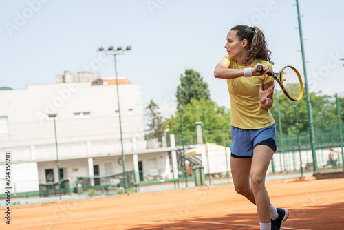 Female player preparing herself to hit the ball, adjusting her stance, tracking its trajectory, and preparing to unleash a skillful and controlled stroke.