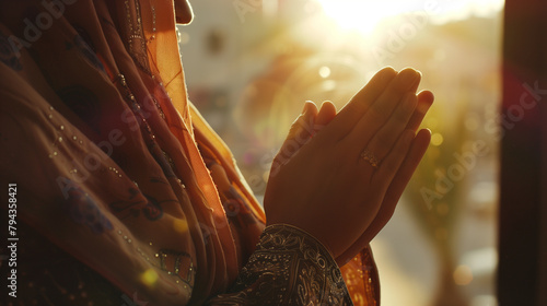 The camera zooms in on the hands of a modern Muslim woman engaged in prayer, with sunlight filtering through nearby windows, casting a gentle glow upon her as she seeks divine sola photo