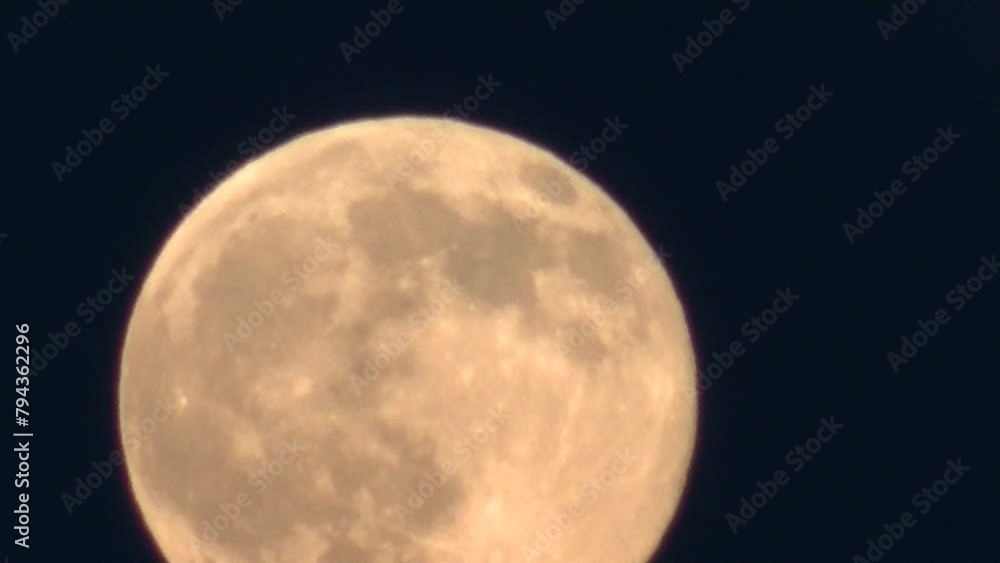 Evening dark sky and slowly moving orange and yellow full moon changing ...