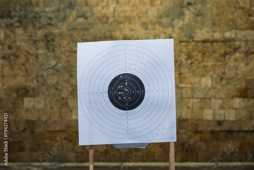 A shooting target with bullet holes in a shooting range in front of a bullet catcher.