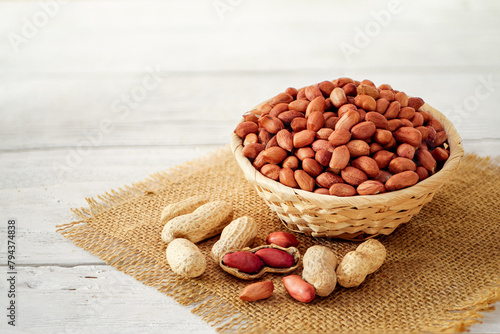Peanuts Heap in a Wicker Basket on a Table Covered with Burlap in a Light Background. Roasted Arachis Nuts Pile, Heap of Peanut, Whole Groundnut with Shell, Macro Peanut Side View on White Background