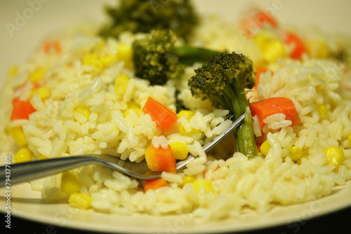 rice with carrots, corn and broccoli on a plate with a spoon