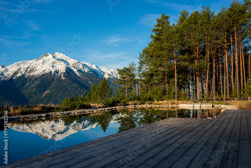 Pristine mountain reflection on the glassy surface of a clear lake surrounded by tall pines.