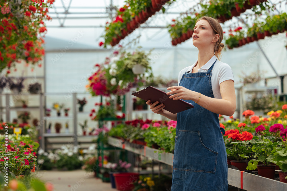 Woman with a clipboard standing in greenhouse