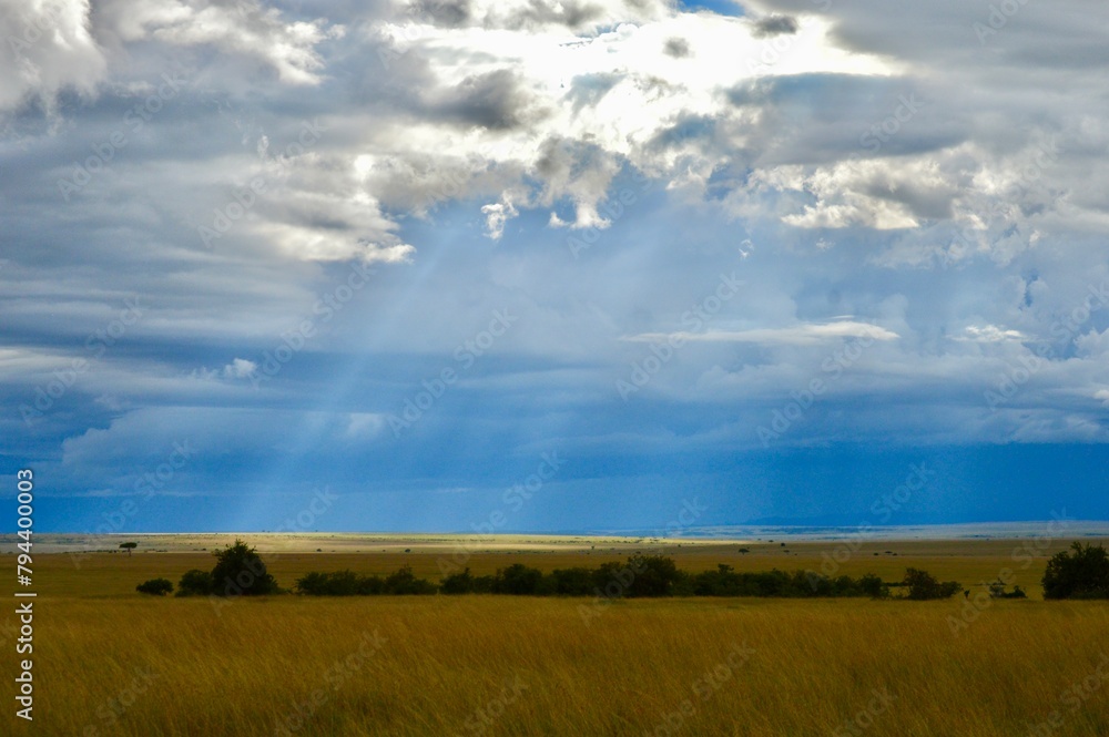 Fototapeta premium Sunlight beaming through clouds in masai mara, kenya
