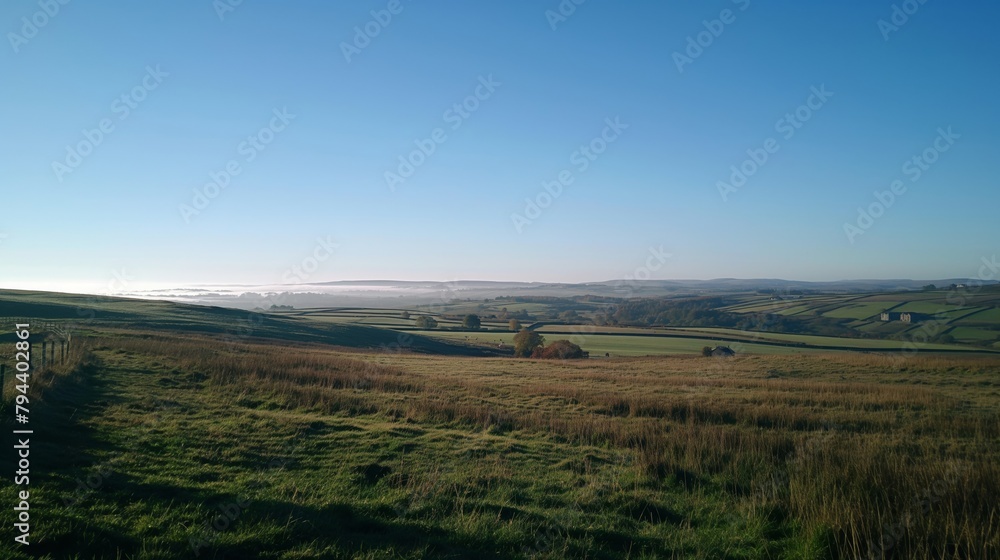 Tranquil view of a countryside with undulating fields and clear blue sky Tranquil view of a countryside with undulating fields and clear blue sky
