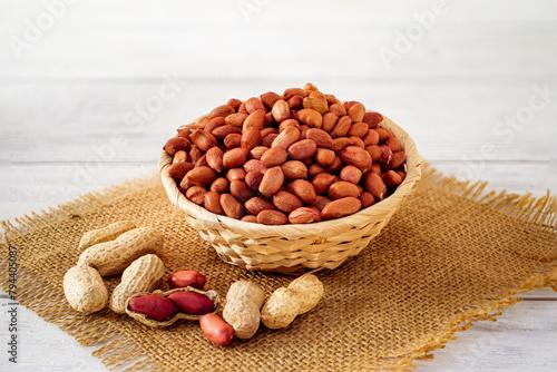 Peanuts Heap in a Wicker Basket on a Table Covered with Burlap in a Light Background. Roasted Arachis Nuts Pile, Heap of Peanut, Whole Groundnut with Shell, Macro Peanut Side View on White Background
