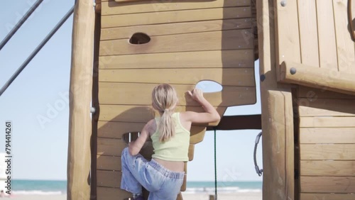 A young girl stands in a wooden playhouse by the water photo