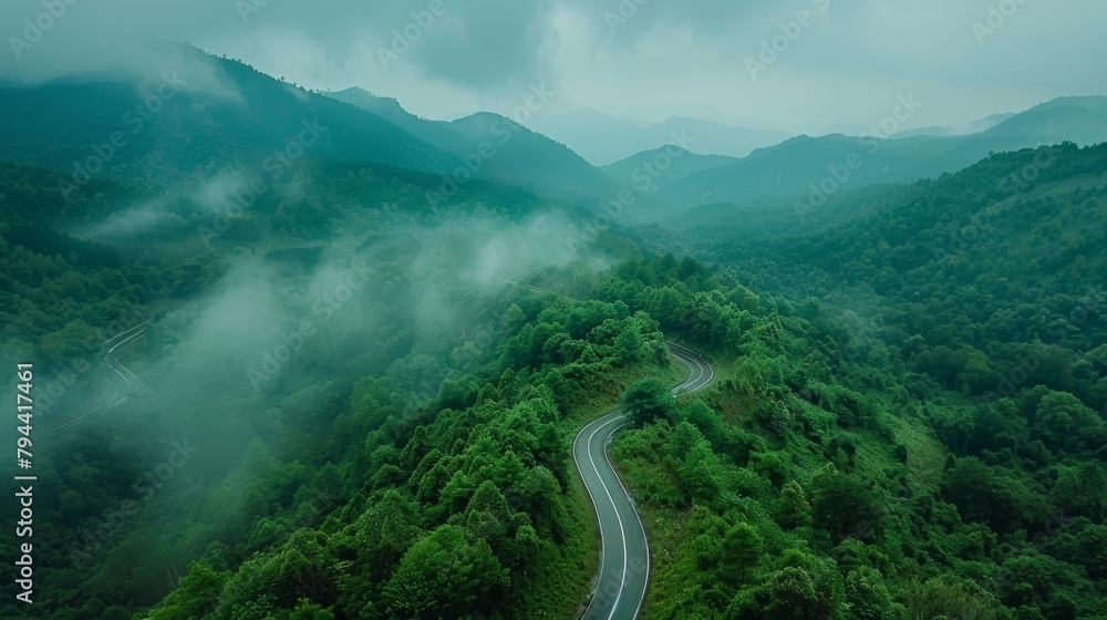 Aerial view of a winding road through a green forest and mountains, aerial photography drone shot with a high resolution top down view, landscape photo panoramic photograph