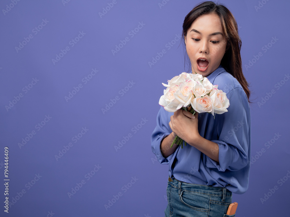 Radiant woman holding a bouquet of roses, blue shirt and jeans, symbolizing joy on a purple background Radiant woman holding a bouquet of roses, blue shirt and jeans, symbolizing joy on a purple background