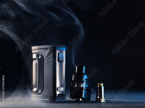 Vaping pod system, refillable cartridge and replaceable vaporizer for electronic cigarette. Black smoky background and copy space.