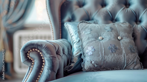 close-up of a light blue, tufted leather armchair with decorative buttons. The focus is on the armrest, displaying intricate designs and metal studs. photo