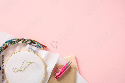Top view cross stitch embroidery accessories. Linen cloth in hoop on pink background photo