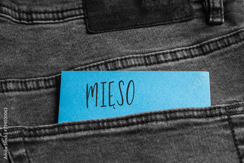 Blue card with a handwritten inscription "Mięso", inserted into the pocket of gray pants jeasnow (selective focus), translation: meat