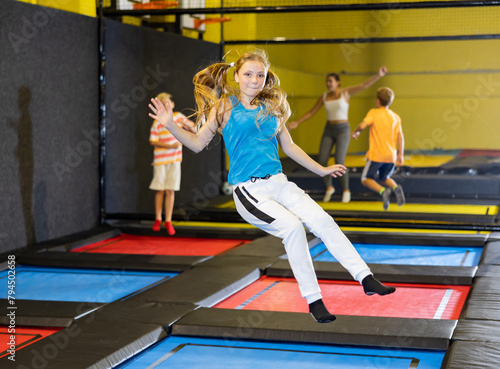 Happy girl jumping on trampoline park in sport center