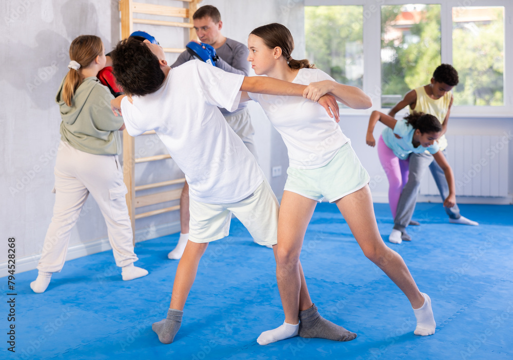 Fototapeta premium Girls and boys learns to do power grip with trainer during a self-defense lesson in the gym