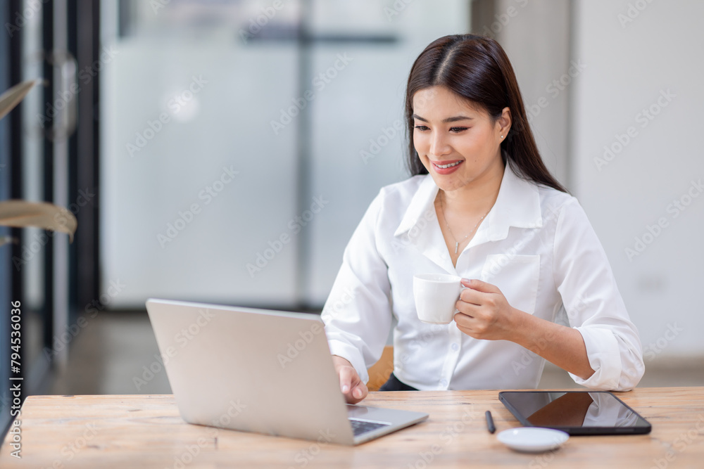 Obraz premium Asian Business woman using calculator and laptop for doing math finance on an office desk, tax, report, accounting, statistics, and analytical research concept 