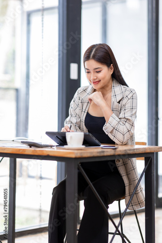 
Portrait of an Asian businesswoman smiling while sitting at her desk.doing planning analyzing the financial report, business plan investment, finance analysis concept.