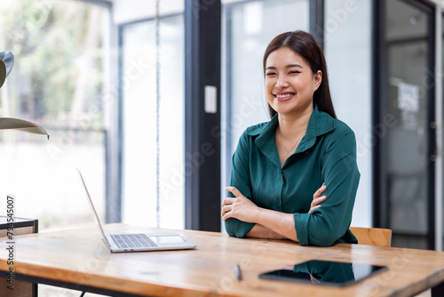 Portrait of happy an Asian businesswoman sitting at her desk office business plan investment, finance analysis concept.Looking at the camera.