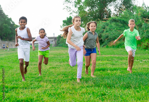 Group of laughing children having fun together outdoors running