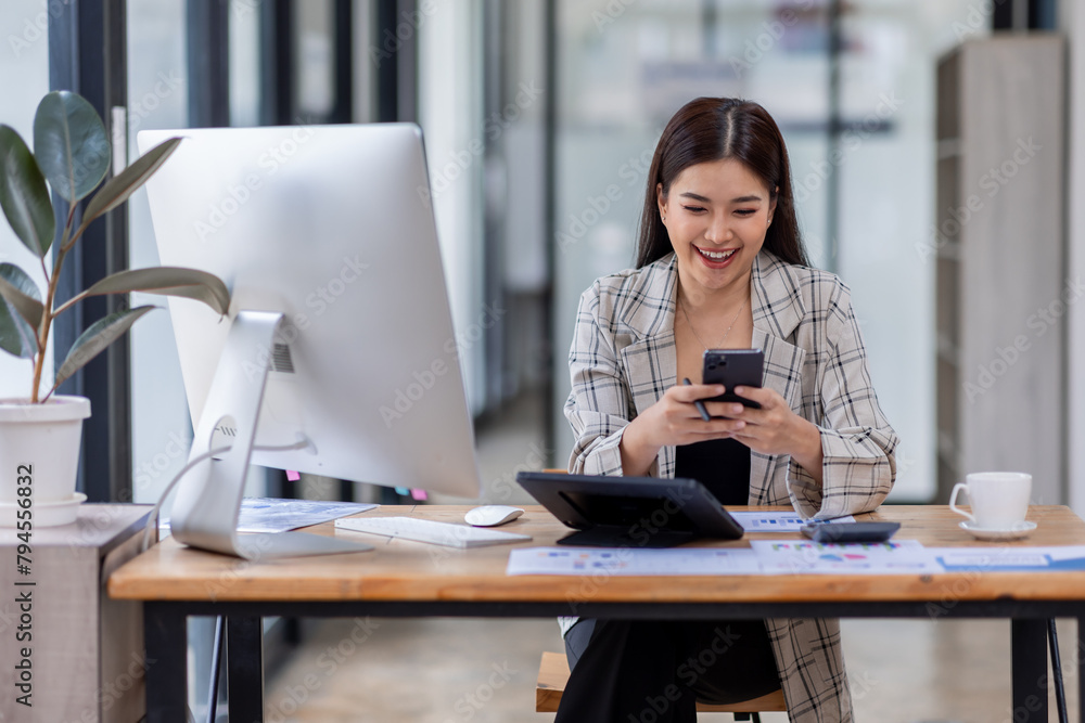 Portrait of young Asian businesswoman in suit, woman smiling and work at workplace inside office, accountant with calculator behind paper phone signing contracts and financial reports Portrait of young Asian businesswoman in suit, woman smiling and work at workplace inside office, accountant with calculator behind paper phone signing contracts and financial reports