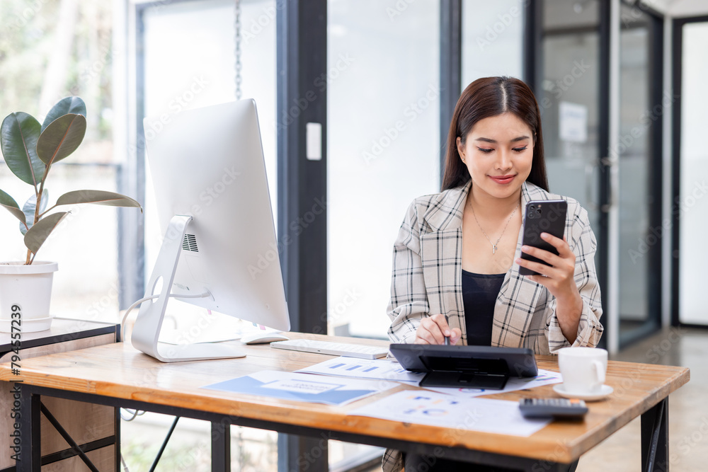 Portrait of young Asian businesswoman in suit, woman smiling and work at workplace inside office, accountant with calculator behind paper phone signing contracts and financial reports Portrait of young Asian businesswoman in suit, woman smiling and work at workplace inside office, accountant with calculator behind paper phone signing contracts and financial reports