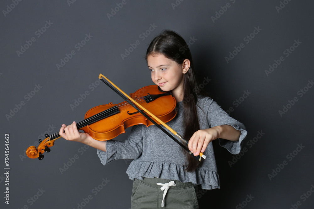 Preteen girl playing violin on black background