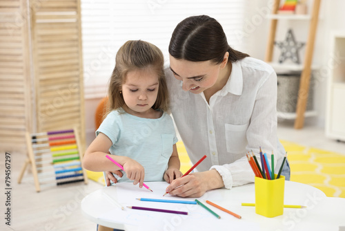 Mother and her little daughter drawing with colorful pencils at home