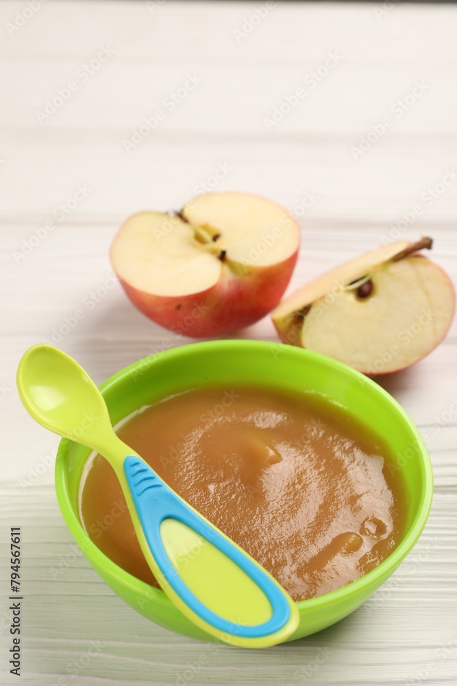 Baby food. Puree of apples in bowl and spoon on white wooden table Baby food. Puree of apples in bowl and spoon on white wooden table