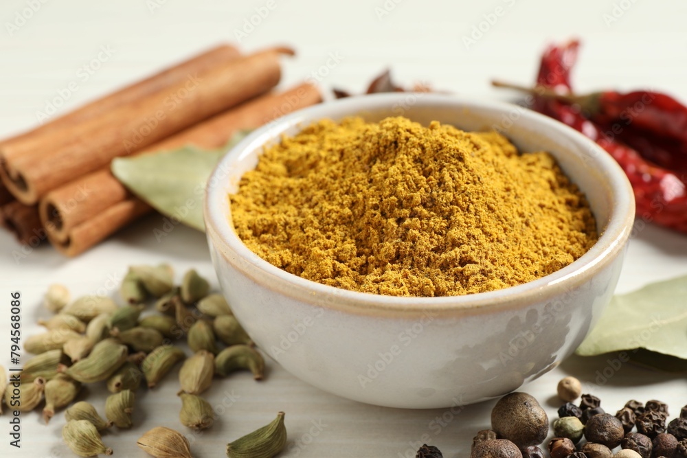 Curry powder in bowl and other spices on white wooden table, closeup Curry powder in bowl and other spices on white wooden table, closeup