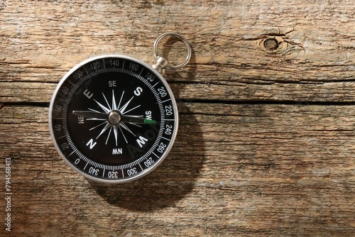 One compass on wooden table, top view. Space for text