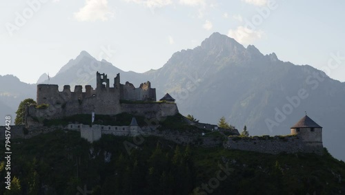 Silhouette of an ancient castle against a backdrop of majestic mountains during sunset.