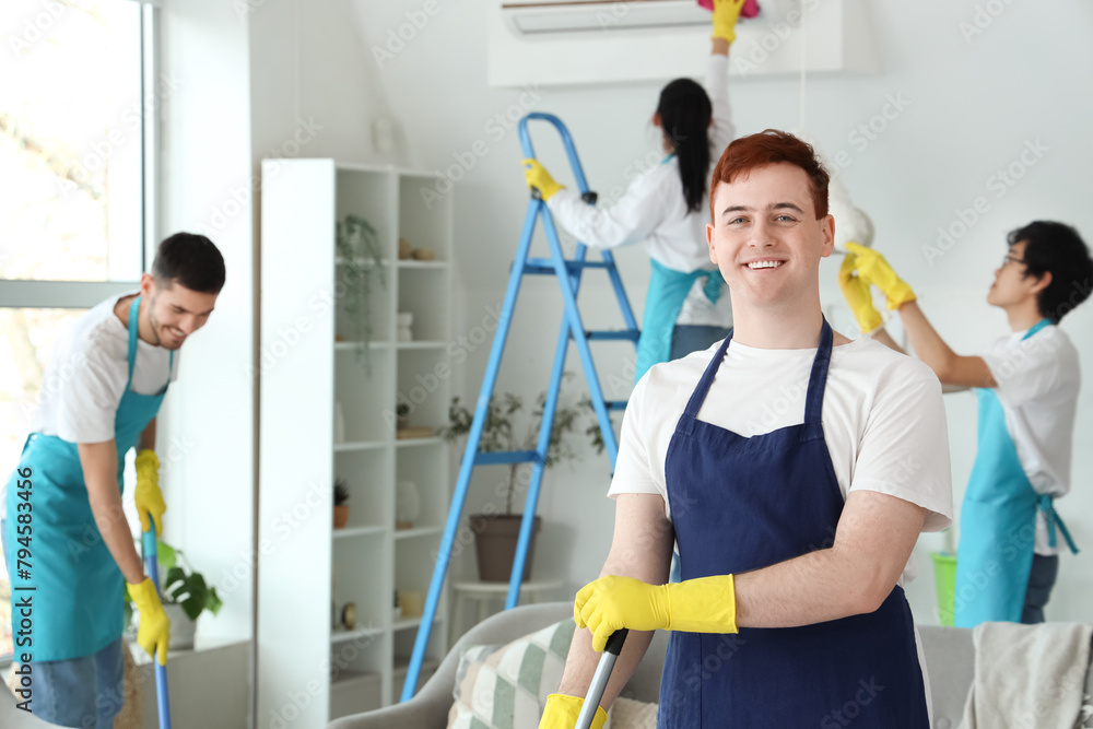 Male janitor with mop cleaning in room Male janitor with mop cleaning in room