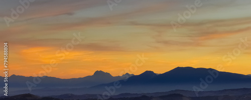 Luminoso tramonto arancio e ocra sopra le montagne italiane photo