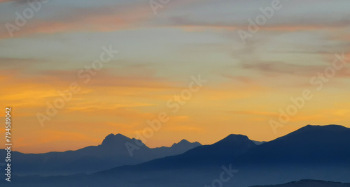 Luminoso tramonto arancio e ocra sopra le montagne italiane photo